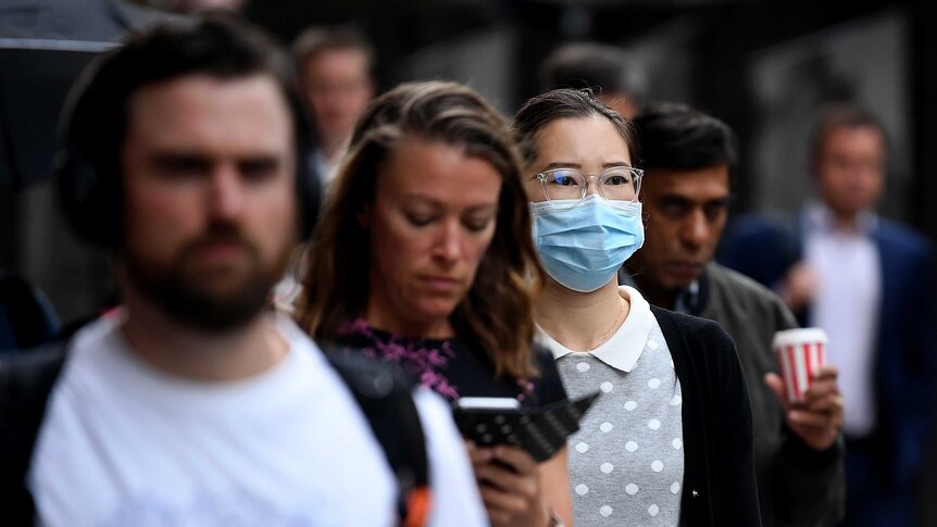 A woman wears a face mask on a crowded street