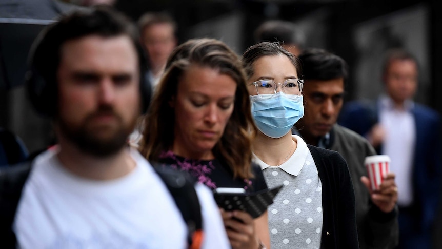 A woman wears a facebmask on a crowded street