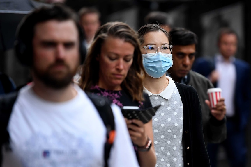 A woman wears a facebmask on a crowded street