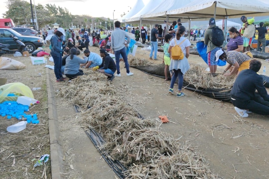 Volunteers make improvised oil-blocking buoys from straw
