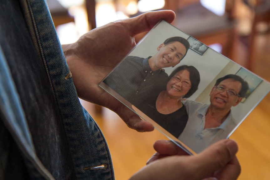 Mikey holding a picture of him with his parents.