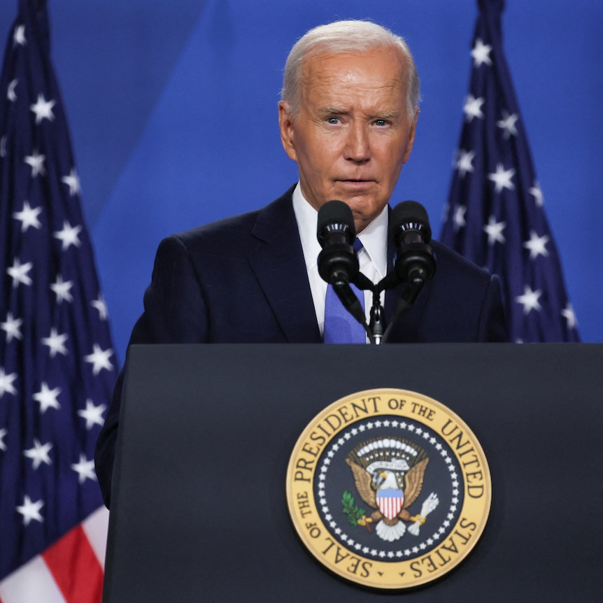 Biden speaks from behind a lectern with American flags behind him