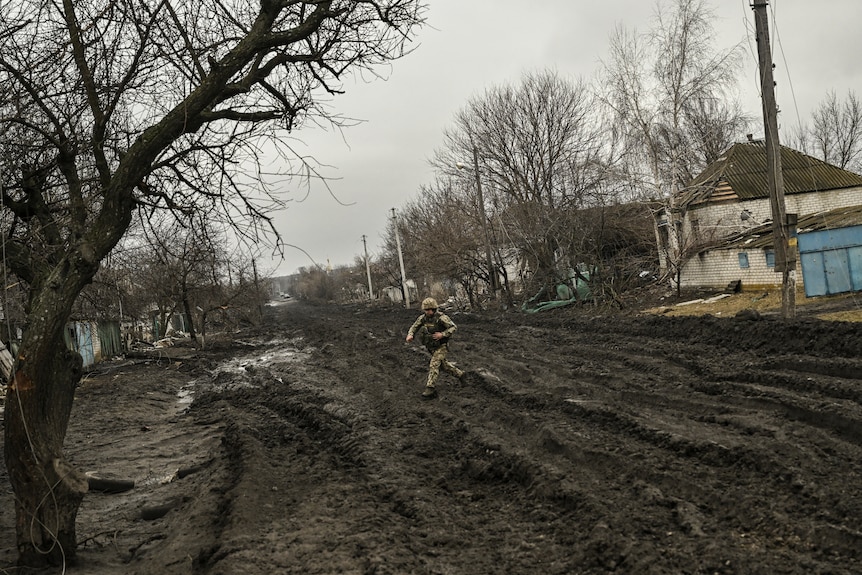 A Ukrainian serviceman crosses a muddy road near Bakhmut.