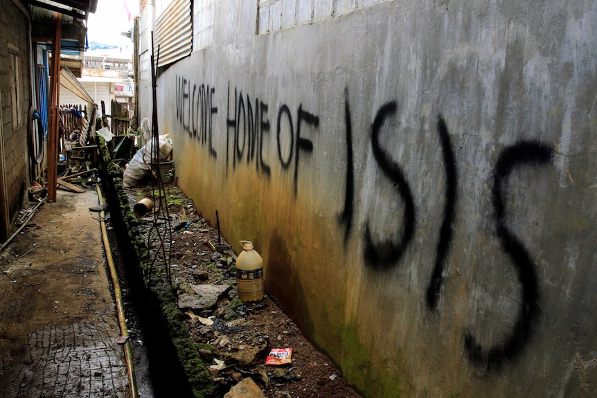 Grafitti that says "Welcome home of ISIS" is seen in a back-alley.