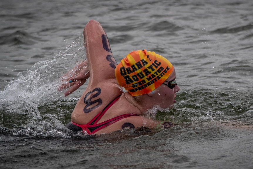Sam Thompson wearing red bathers and an orange cap competing in an open water race