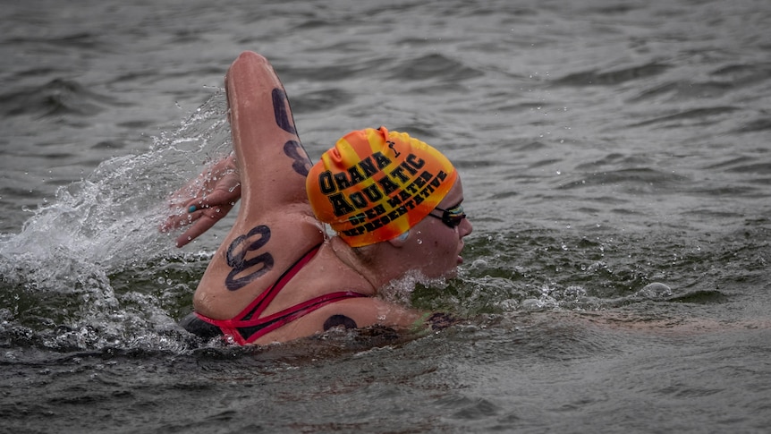 Sam Thompson wearing red bathers and an orange cap competing in an open water race