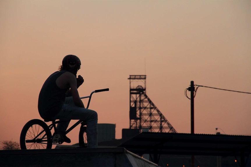 A young man looks out at the mine in Mount Isa as the sun goes down.