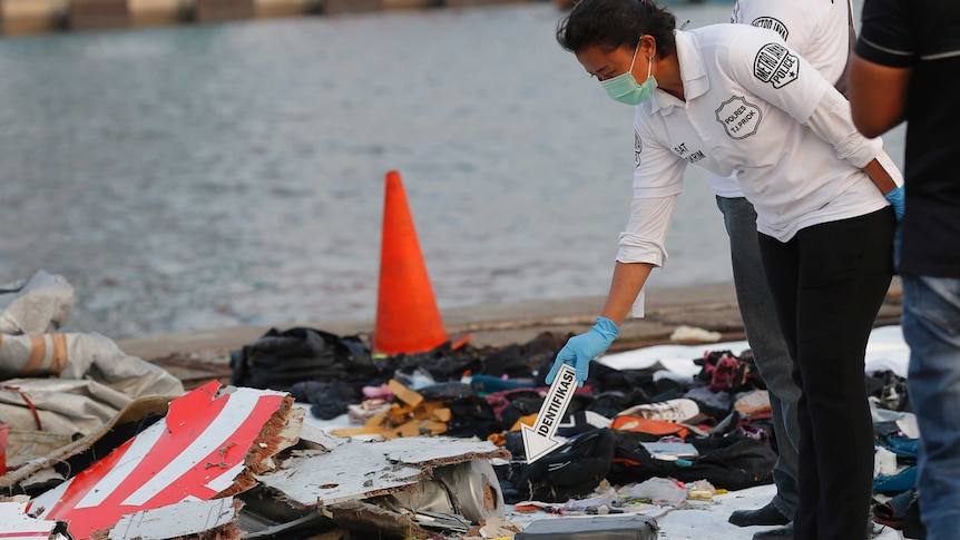 A police officer inspects debris recovered from the area where a Lion Air passenger jet crashed