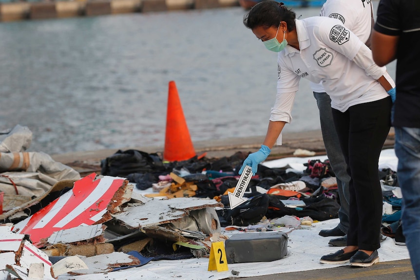 A police officer inspects debris recovered from the area where a Lion Air passenger jet crashed