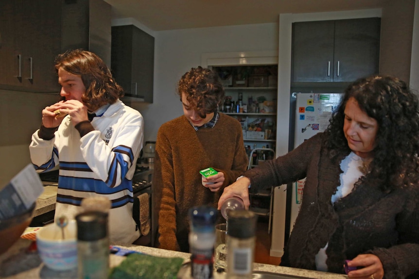 Louis and Walter Smithers and their mother, Carolyn Merritt, prepare food in their kitchen.