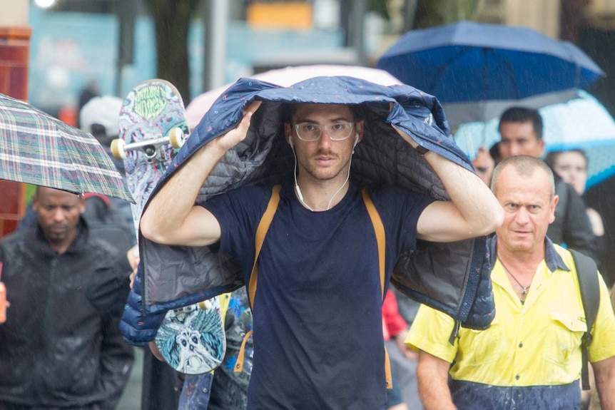 A man seeks shelter under is jacket as Melbourne braces for heavy storms on Friday, 1 December 2017.