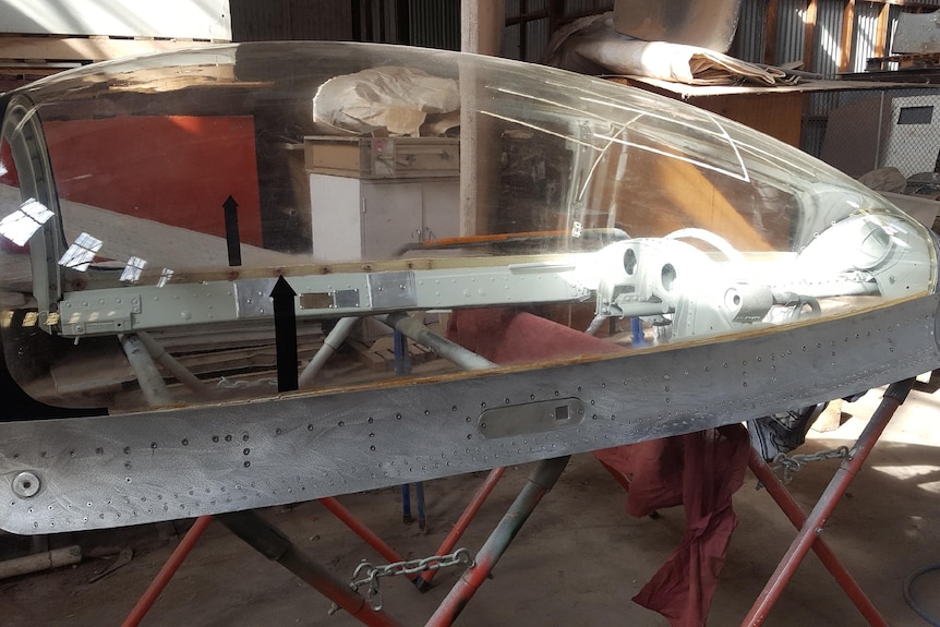 A perspex plane cockpit canopy sitting on a stand.