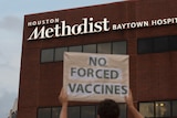 A protester holds a sign saying 'no  forced vaccines' in front of the Houston Methodist Baytown Hospital 