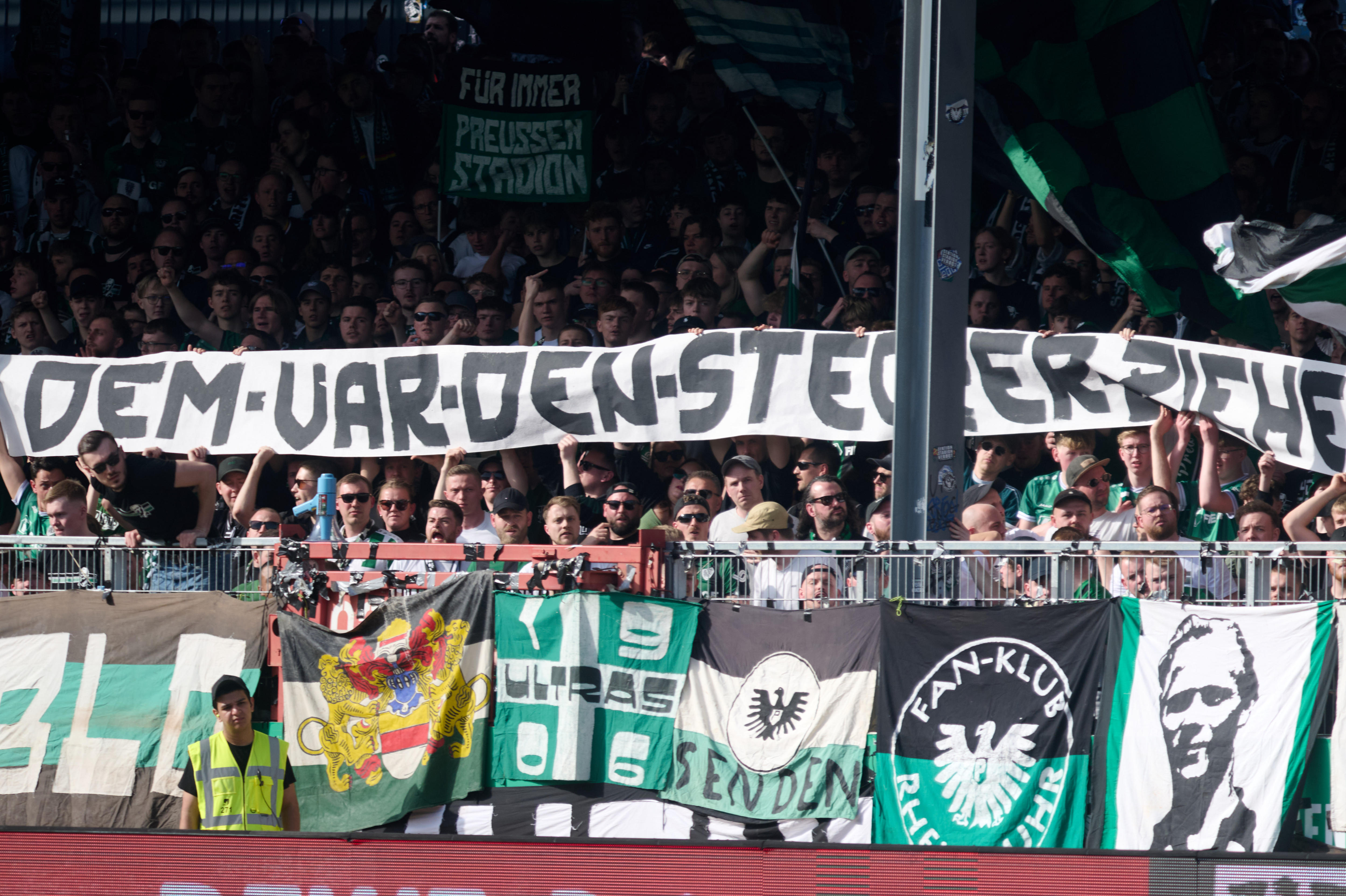 A group of fans at a German football game sit near a banner that translates as: 'Pull the plug on the VAR'.