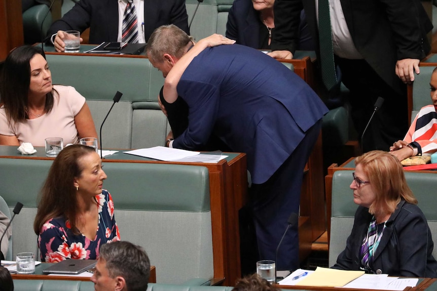 Bill Shorten leans down to hug Susan Lamb. Emma Husar watches on with other Labor MPs.