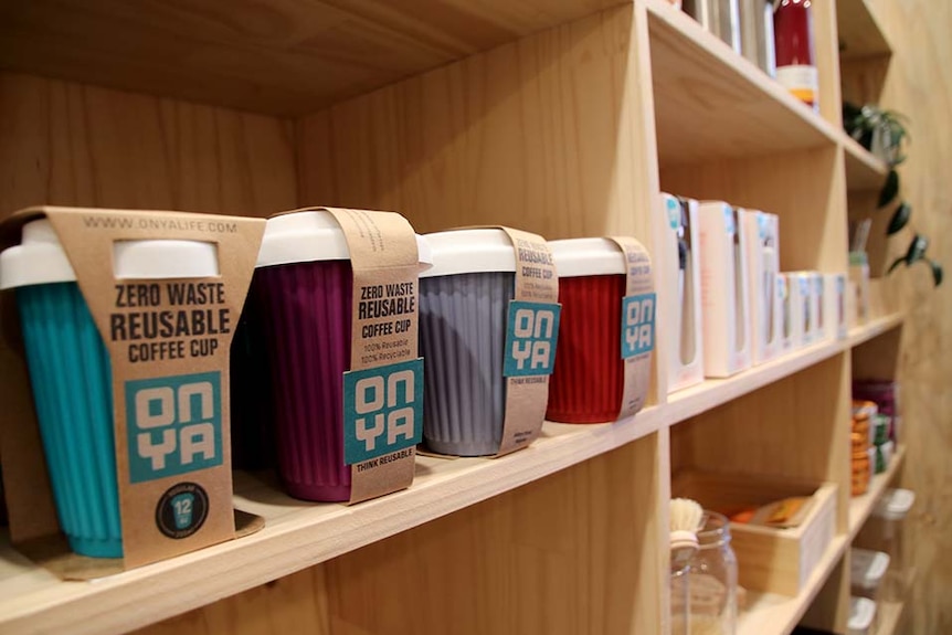 Reusable coffee cups on a shelf in a shop