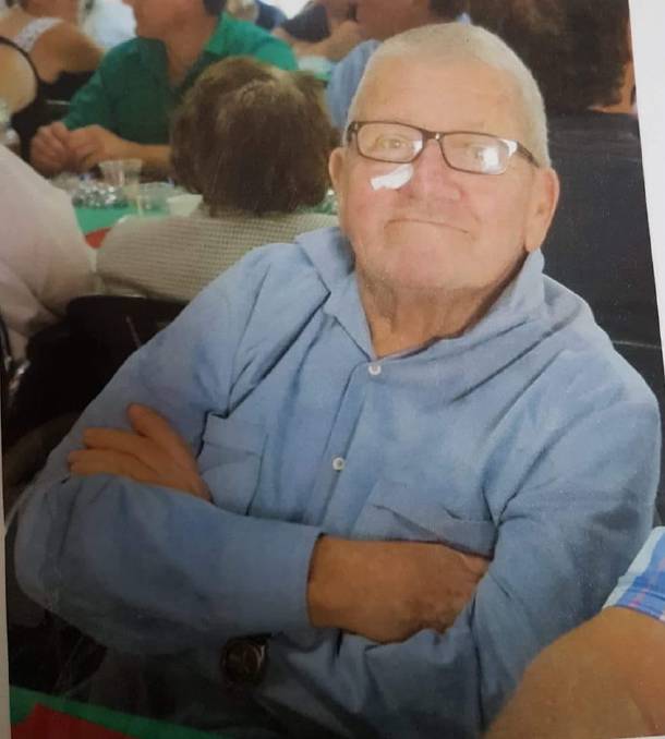 An elderly man smiles at the camera. 