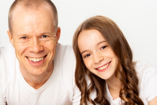 A dad and daughter smile for a photo. 