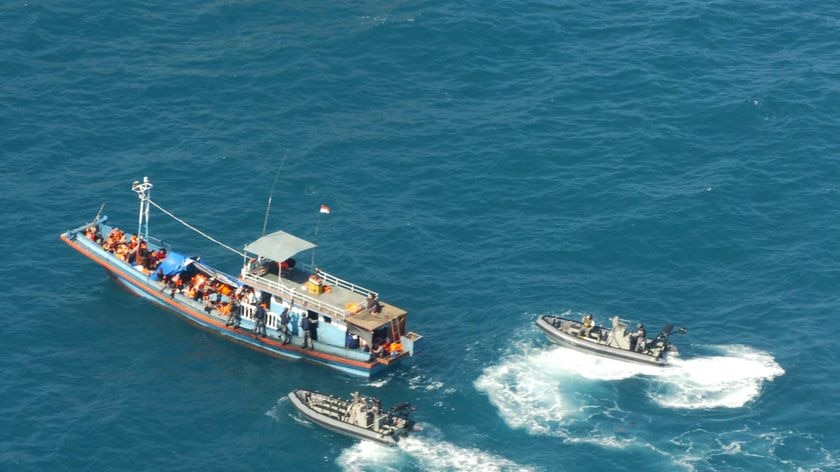 A Navy patrol boat and two other vessels escort one of the boats carrying asylum seekers off the north Australian coast.