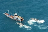 A Navy patrol boat and two other vessels escort one of the boats carrying asylum seekers off the north Australian coast.