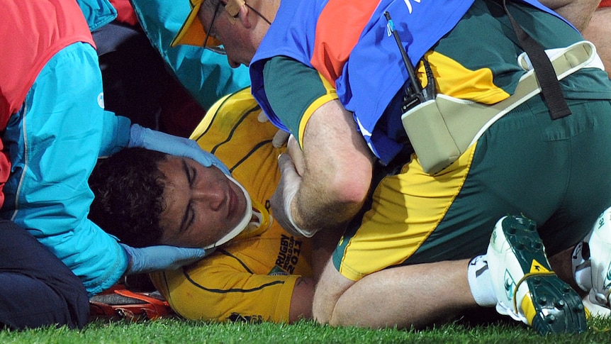 Wallabies centre Anthony Faingaa is fitted with a neck brace after being hit the head with a stray knee.