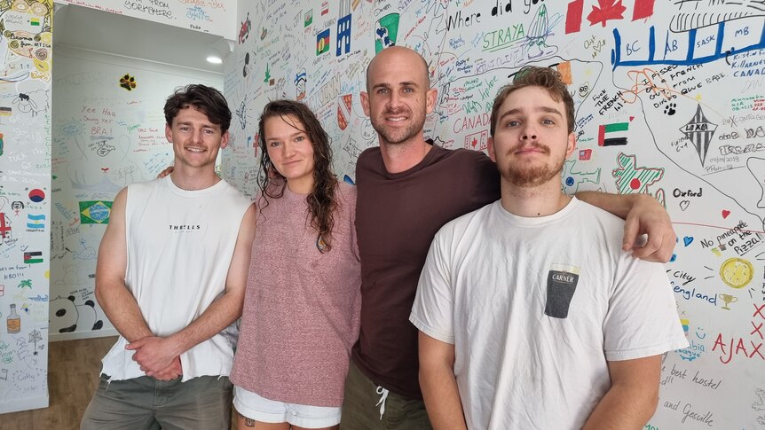Four people stand in the foyer of a backpacker hostel.