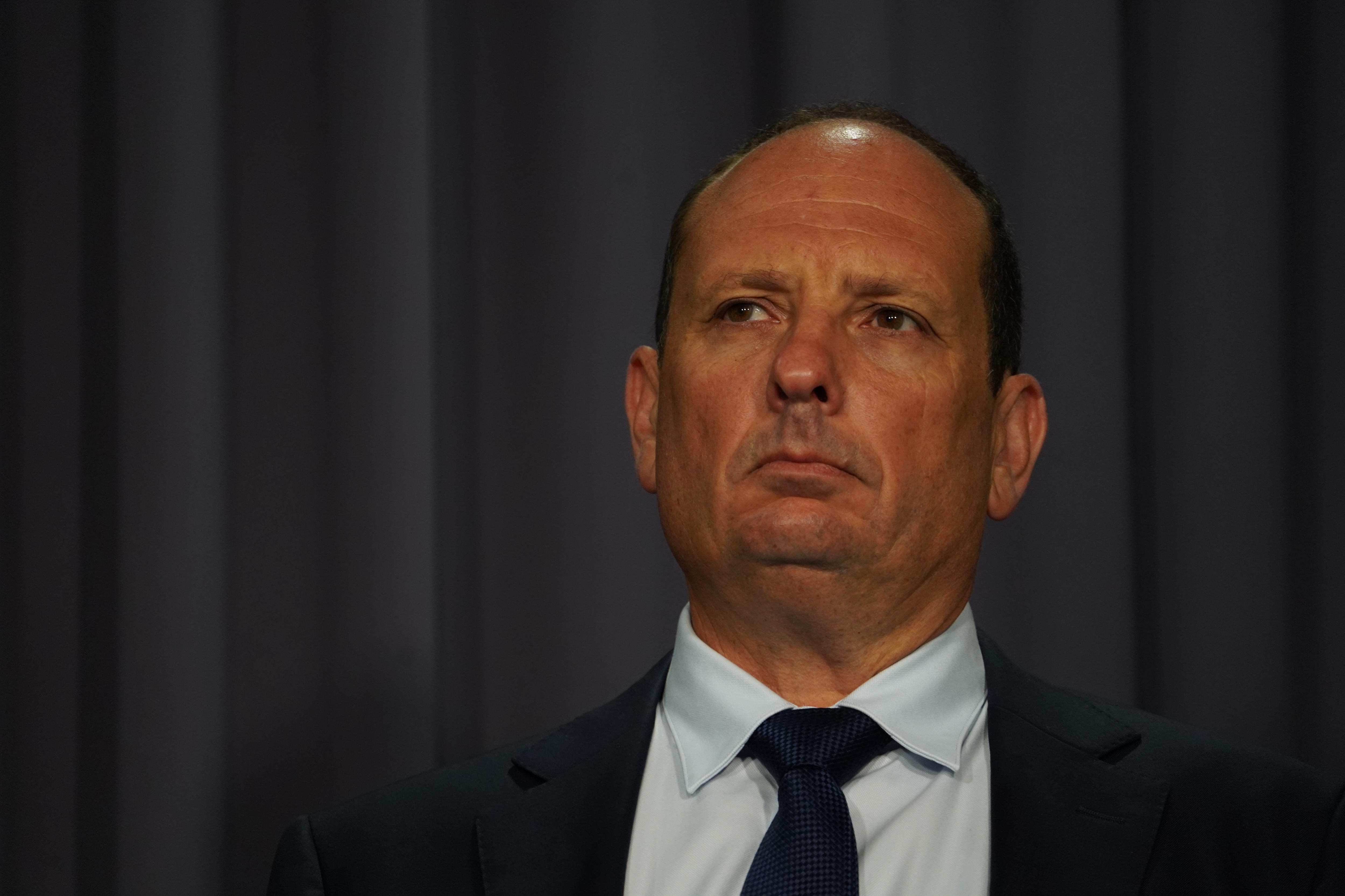 Un primer plano del rostro de un hombre mirando fuera de la pantalla, vestido con traje y corbata.