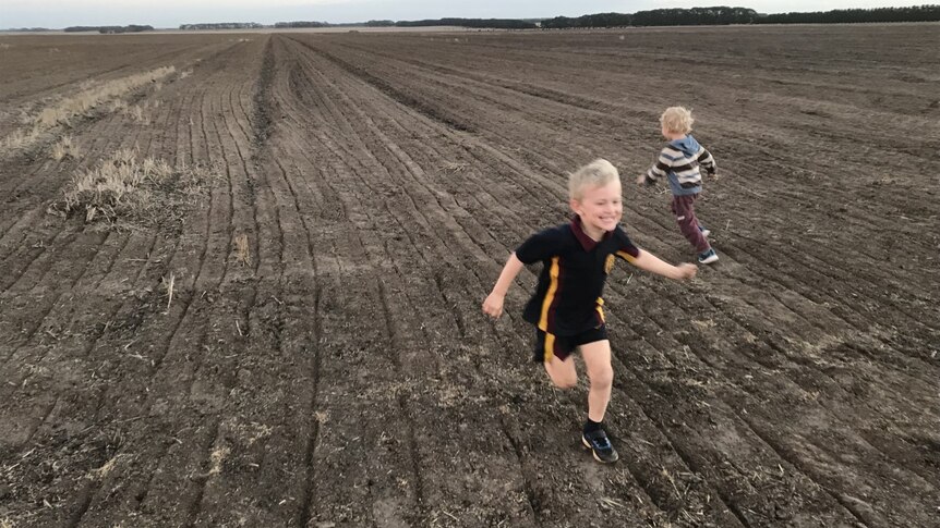 Kirsten's two sons run around a paddock on their farm in country Victoria.