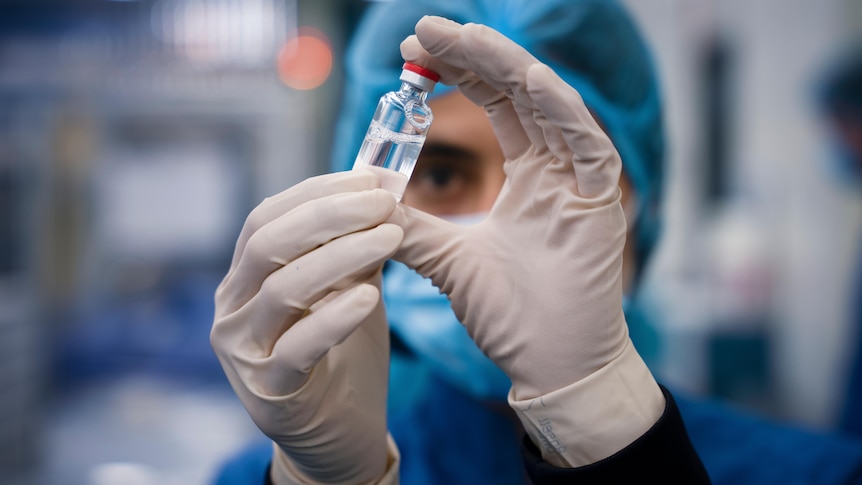 一名医疗人员查看疫苗的瓶子。