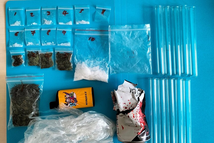 Bags of methamphetamine or "ice", cannabis, weigh scales and other drug paraphernalia laid out on a table. 