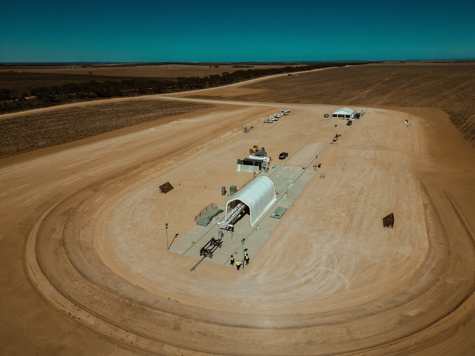 An overhead shot of vast red outback soil with some small buildings in the middle