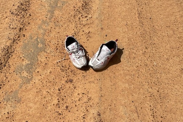 A pair of sneakers on a red dirt track.