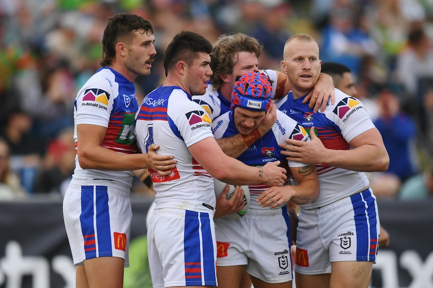 NRL players gather around their teammate who has just scored. 