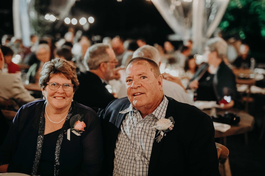 An older couple sitting together dressed up during a dinner event