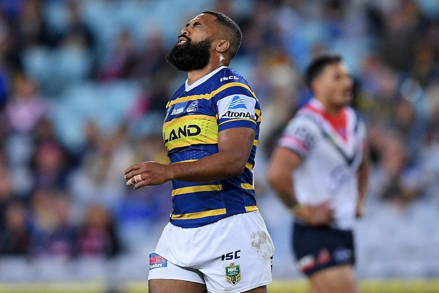 Michael Jennings grimaces with his eyes closed playing for Parramatta against the Sydney Roosters.