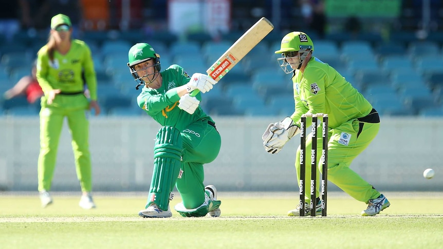 A WBBL cricket player gets on one knee to sweep the ball square of the wicket.