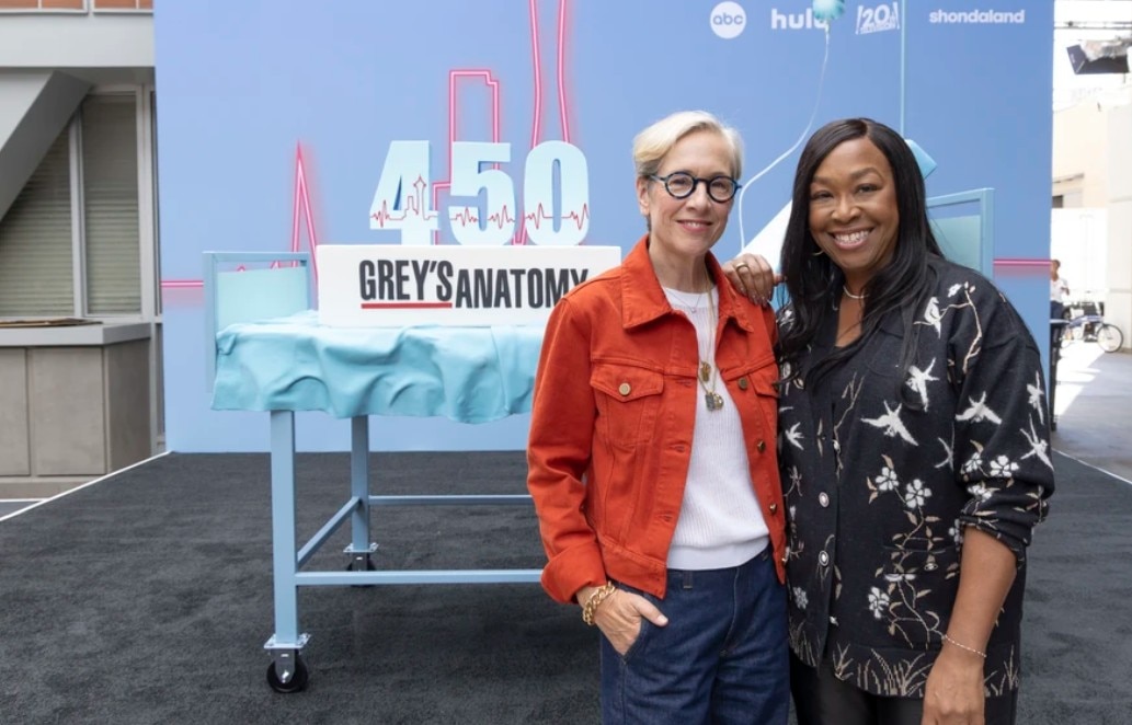 Dos mujeres se paran frente a un gran pastel.
