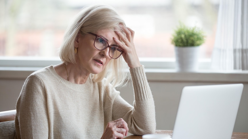 An older women looks perplexed at a laptop screen