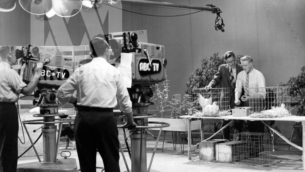 An old black and white photo of an ABC studio with presenters and cameramen during filming