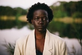 A young black woman wearing a cream blazer stares at the camera.