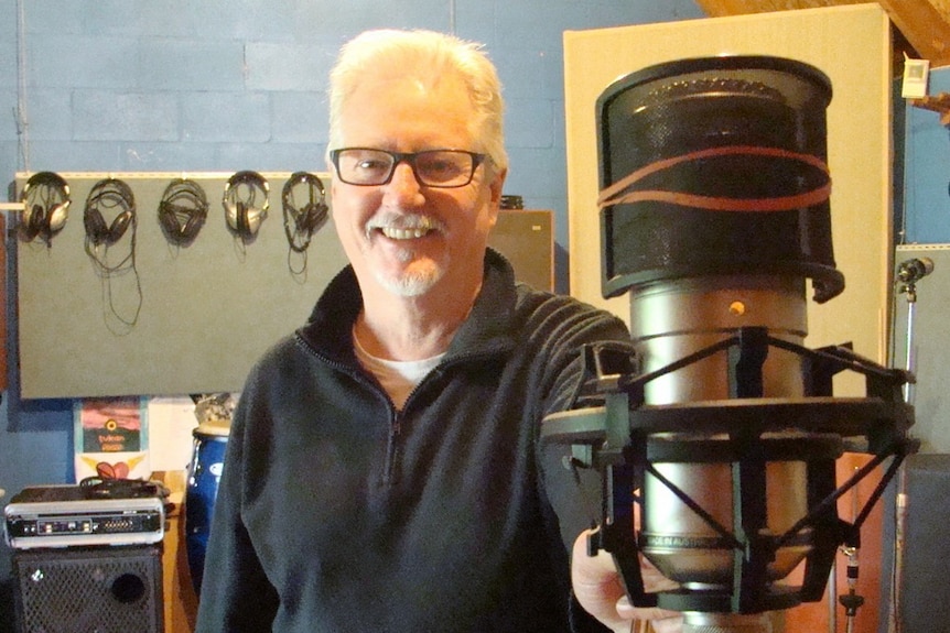 A man stands near a recording microphone
