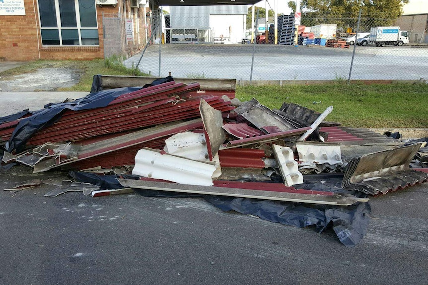A pile of roof materials and other building materials on the side of the road.