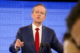 Bill Shorten points as he speaks at a podium.