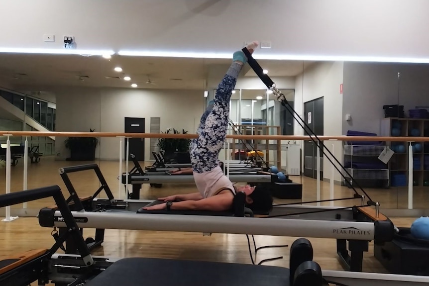 A photo of a woman lying on am exercise table with her legs in the air.