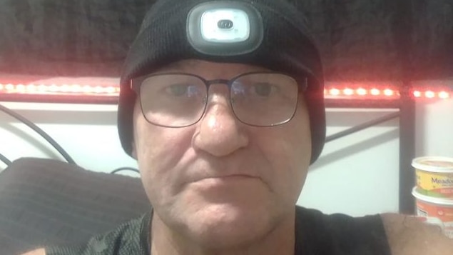 a man in a beanie sitting in front of a pirate skull and crossbones flag