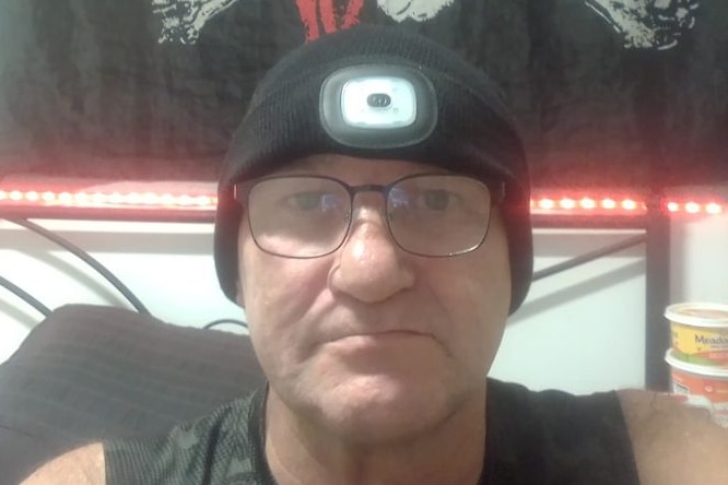 a man in a beanie sitting in front of a pirate skull and crossbones flag