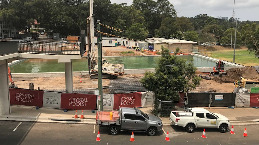 A large swimming pool with construction equipment and trucks around the outside.