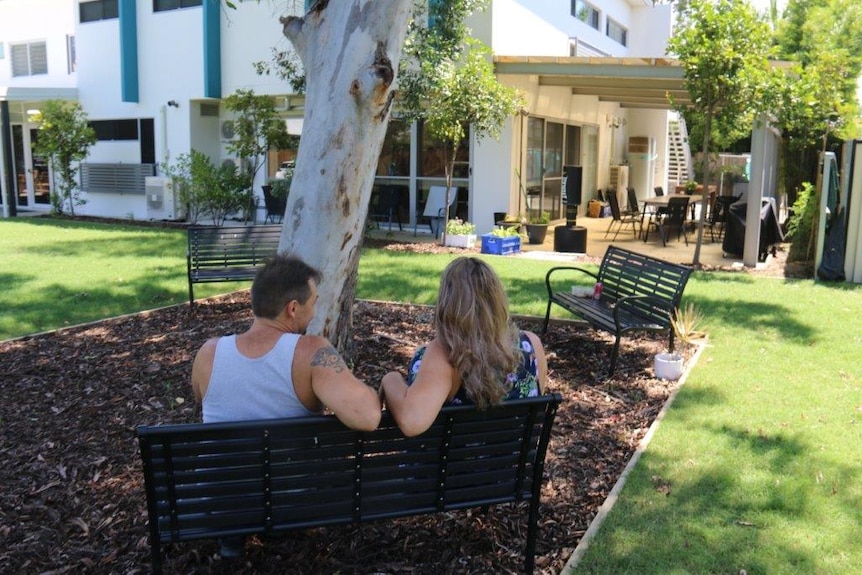 Two anonymous patients sit on a park bench on a sunny day at the Queensland facility.