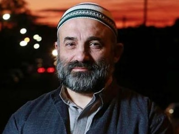 Keysar Trad poses for a photo wearing a traditional Muslim cap on his head.