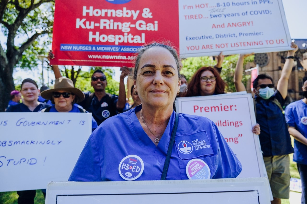 A woman looking at the camera with signs behind her